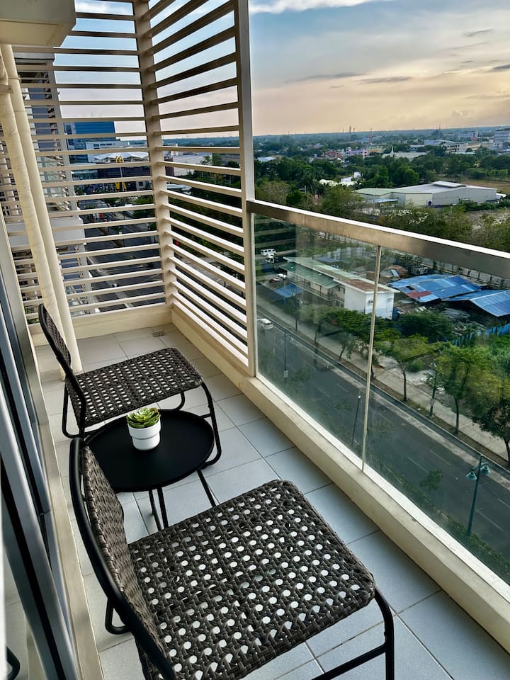 Private balcony with rattan chairs and a wide city view at dusk