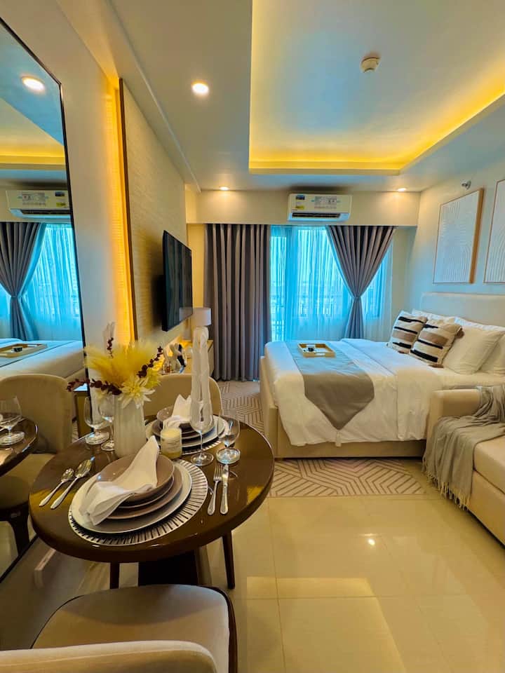 Bright one-bedroom interior with bed, sofa, dining table and wall-mounted TV