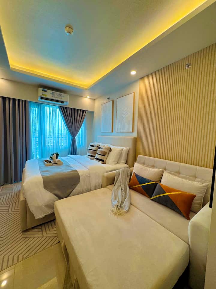 Bed alongside a chaise sofa under cove lighting